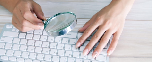 Vrouw kijkt naar het toetsenbord met een vergrootglas