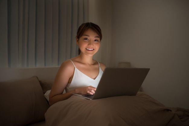 Vrouw kijkt naar laptop in bed