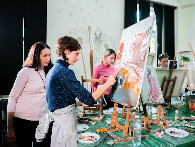 Vrouw kijkt naar schilder schilderij in studio