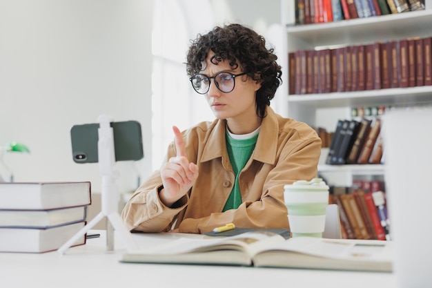 Vrouw kijkt naar webinar vanaf de telefoon in kantoorcoworking of bibliotheekwerk en studeer online