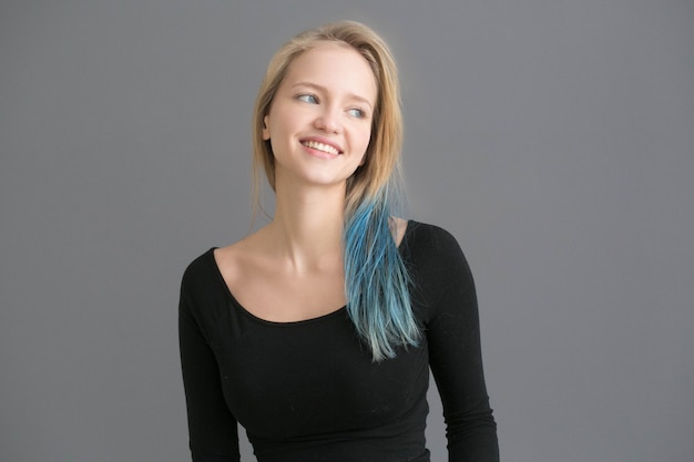 Vrouw kleur haar met blauw gekleurd kapsel ower grijze muur. Studio opname.