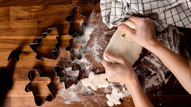 Vrouw kneedt deeg. Gemberkoekjes op houten tafel. Gezellig thuis koken. Thuis bakken.