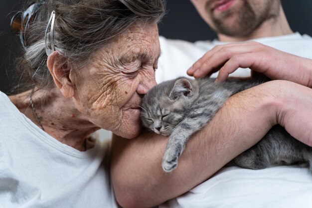 Foto vrouw knuffelen en kussen om kleine schattige grijze kitten onder ogen te zien