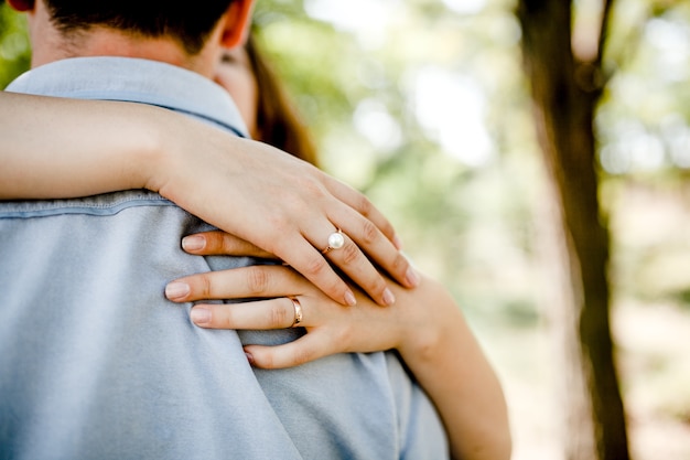 Vrouw knuffelen man, close-up op handen met verlovingsring