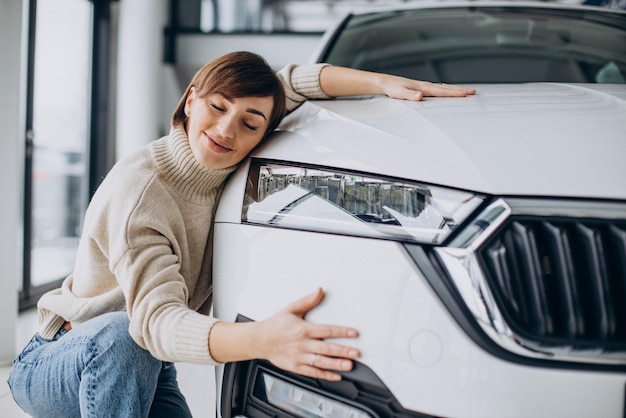 Vrouw knuffelt auto in een autoshowroom