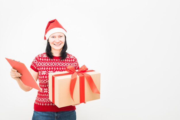 Vrouw koerier in kerstmuts en kerst trui houden geschenk