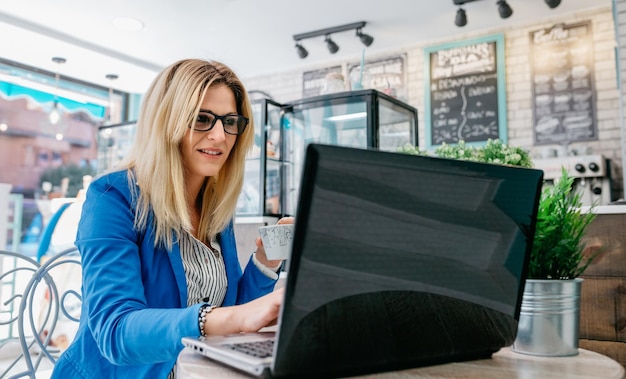 Vrouw koffie drinken en chatten met de laptop in een coffeeshop