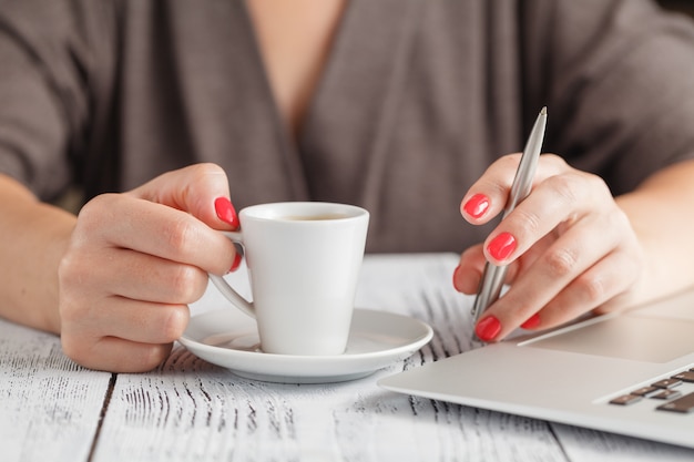 Vrouw koffie drinken en het gebruik van digitale tablet in de ochtend