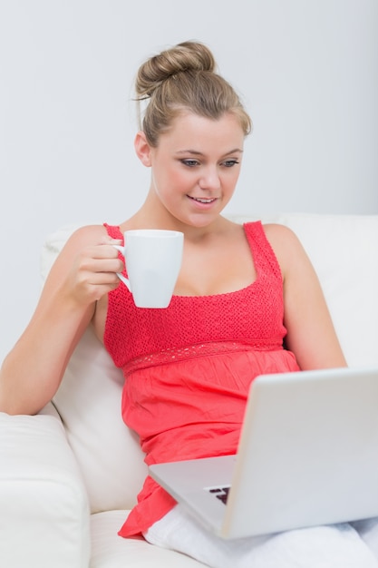 Vrouw koffie drinken tijdens het gebruik van de laptop