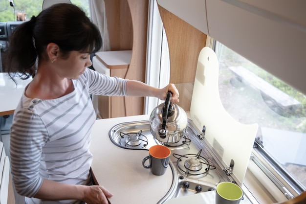 Vrouw koken in camper, camper rv interieur. familie vakantiereizen, vakantiereis in camper, caravan autovakantie.