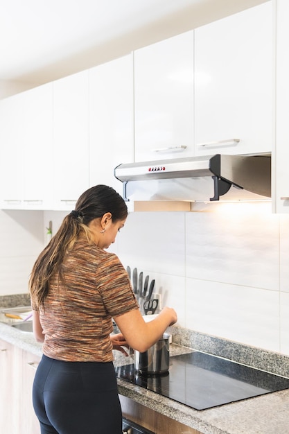 Vrouw kookt in de keuken op een inductiekookplaat met geurafzuiger