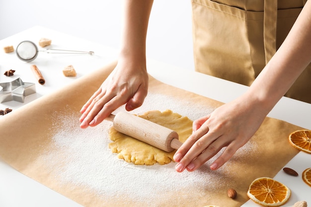 Vrouw kookt koekjes met koekjessnijder en deegroller