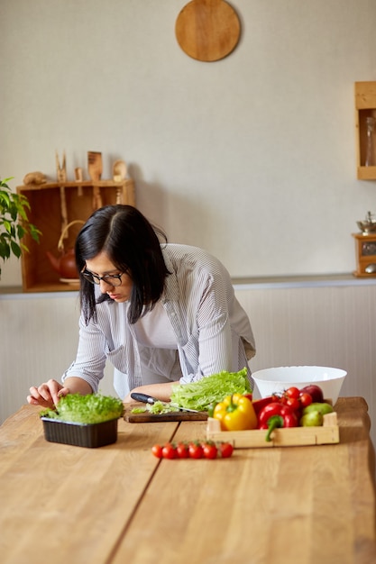 Vrouw kookt thuis in de keuken, met behulp van digitale tablet of smartphone