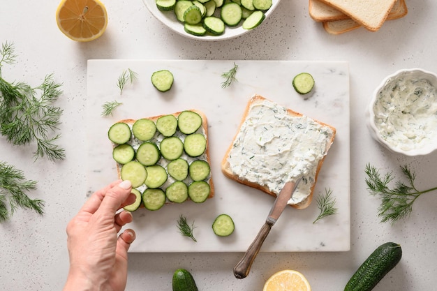 Vrouw kookt traditionele Engelse theekomkommersandwiches met ricotta en dille als ontbijt