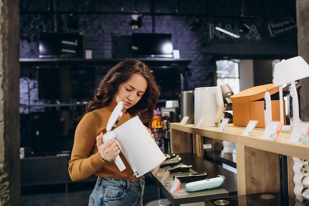 Foto vrouw koopt een waterkoker in de winkel promoties en kortingen op apparatuur