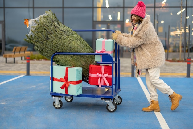 Vrouw koopt kerstboom en cadeautjes in winkelcentrum