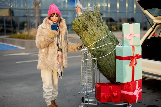 Vrouw koopt kerstboom en cadeautjes in winkelcentrum