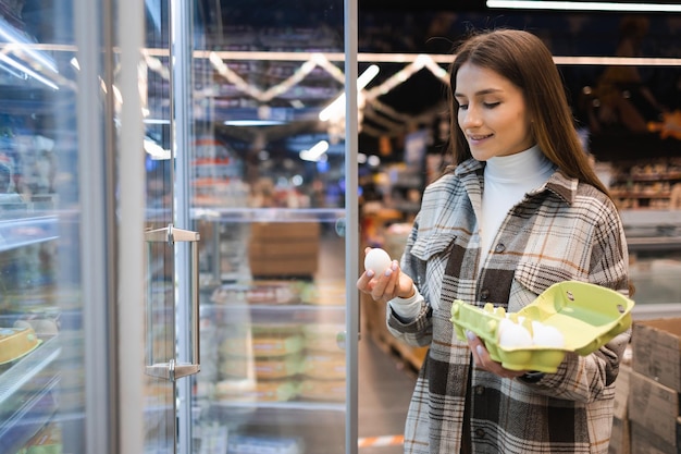 Vrouw koopt kippeneieren in supermarkt