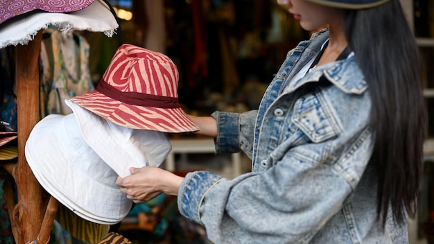 Vrouw koopt lokale kleurrijke hoeden in de plaatselijke winkel tijdens reisvakantie of vakantietijd