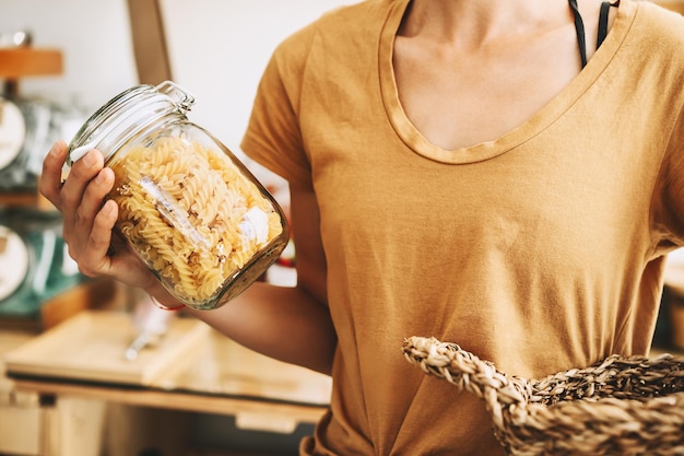 Vrouw koopt producten in plasticvrije supermarkt Glazen pot met pasta in handen van persoon in afvalloze winkel Jong meisje met rieten mand maakt bewust winkelen Duurzame kleine bedrijven