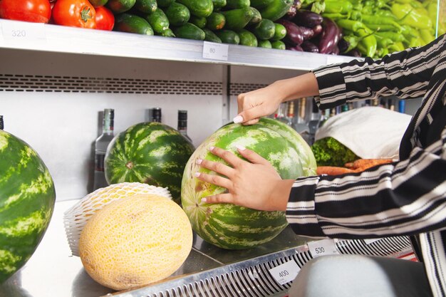 Vrouw koopt watermeloen in voedingswinkel