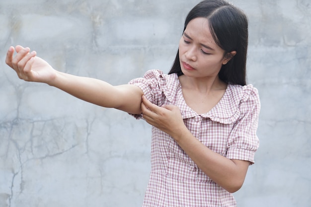 Foto vrouw krabt arm van jeuk op grijze achtergrond