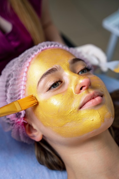 Vrouw krijgt gezichtsmasker door schoonheidsspecialiste in de spa salon. Breng gezichtsmasker, spa schoonheidsbehandeling en huidverzorging aan.