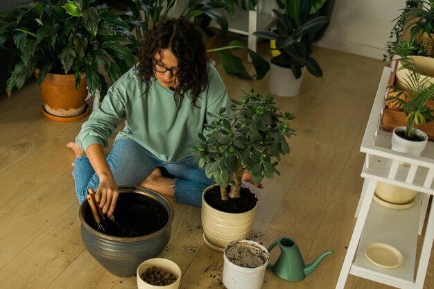 Foto vrouw kweekt potplanten thuis water geven en bloemen verzorgen, tuinieren en kamerplanten verzorgen
