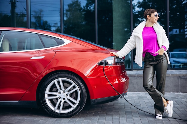 Vrouw laadt elektrische auto op bij het kantoorgebouw