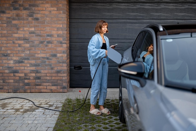 Vrouw laadt haar elektrische auto bij een huis op