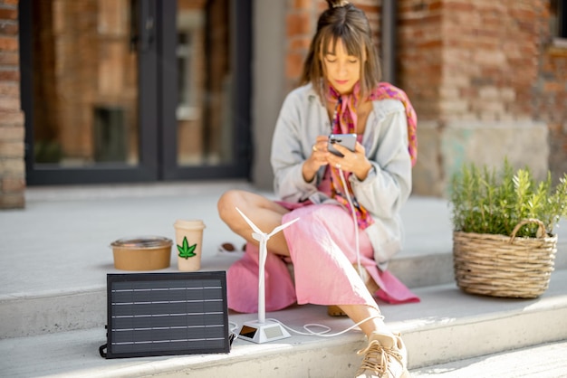 Vrouw laadt telefoon op vanaf een draagbaar zonnepaneel