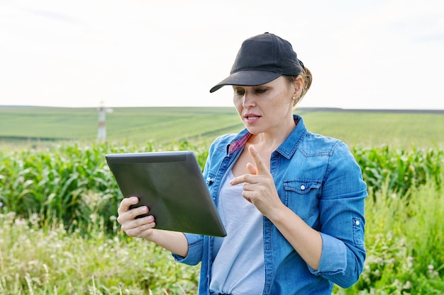 Vrouw landbouwarbeider inspecteren maïsveld video-oproep met behulp van digitale tablet