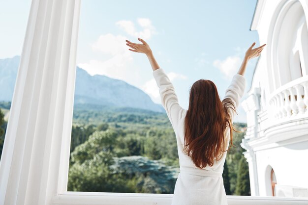 Vrouw lang haar in een witte badjas verblijft op het balkon in een hotel Mountain View