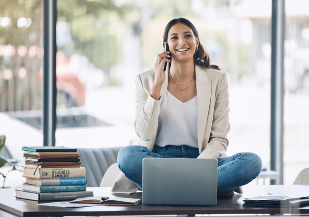 Vrouw laptop en telefoongesprek en zittend op bureau in ontspannen startup marketingbedrijf of reclamebedrijf Glimlach blij en pratende werknemer op laptop voor mobiele communicatietechnologie of boekenstudie