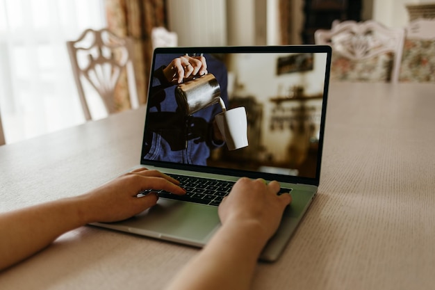 Vrouw leert koffie te zetten terwijl ze online lessen op een laptop bekijkt