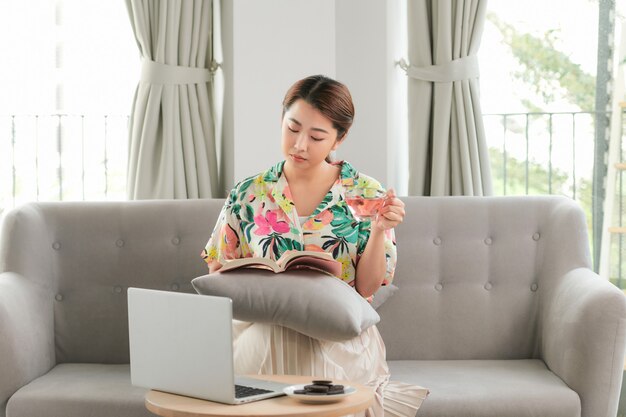 Vrouw leesboek met kopje koffie thuis in de woonkamer