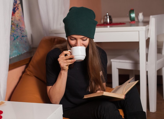 Vrouw leest boek en drinkt thee in café