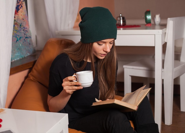 Vrouw leest boek en drinkt thee in café