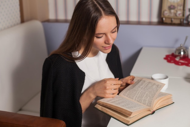 Vrouw leest boek in café en drinkt thee