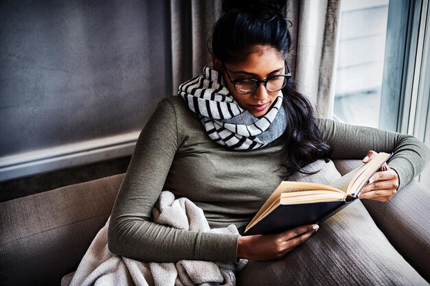 Foto vrouw leest boek op de bank