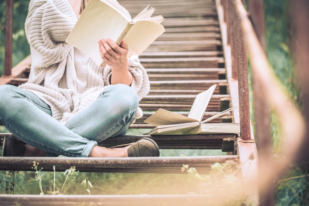 vrouw leest een boek op de trappen van een trap