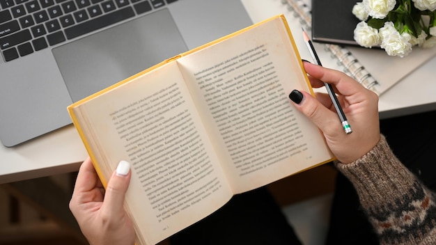 Vrouw leest een nieuw boek in haar kantoor aan huis Vrouw zoekt informatie op notebook