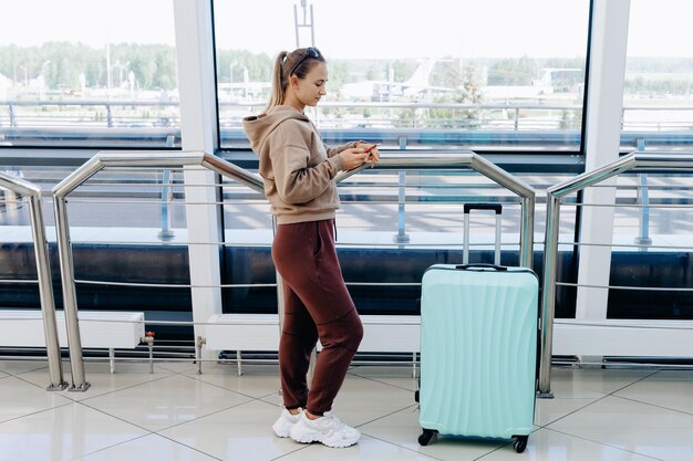 Vrouw leest een sms terwijl ze op de luchthaven staat