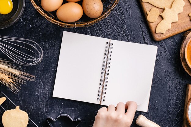 Vrouw leest kookboekrecept voor het maken van Halloween-koekjes met bakingrediënten ontwerpconcept van kookles bovenaanzicht plat boven het hoofd