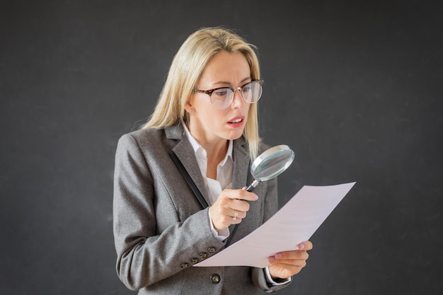 Vrouw leest zorgvuldig zakelijk contract met vergrootglas