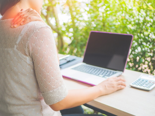 Vrouw legde haar hand op haar nek terwijl ze pijn voelde. Office-syndroom concept.