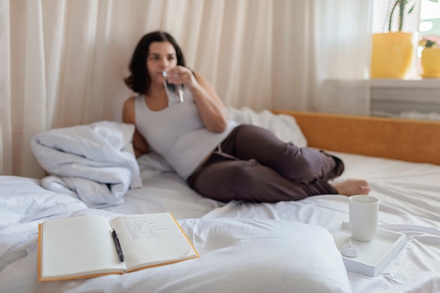 Vrouw liggend in bed, drinkwater naast dagboek