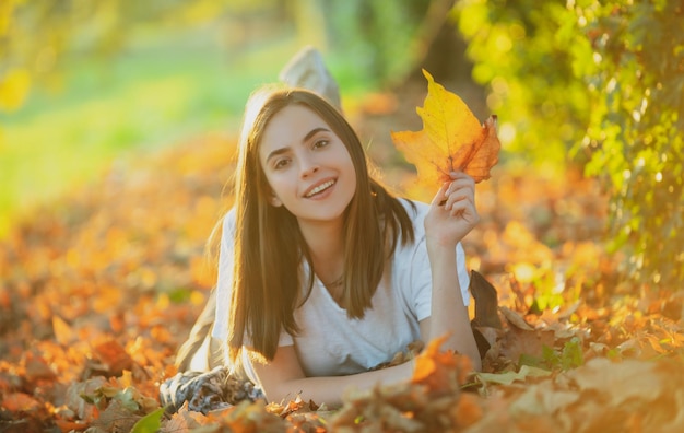 Vrouw liggend in herfst herfstbladeren in park jonge vrouw en herfstweer