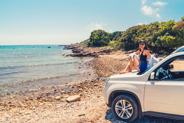 Vrouw liggend op auto kap met uitzicht op zee zomer strand