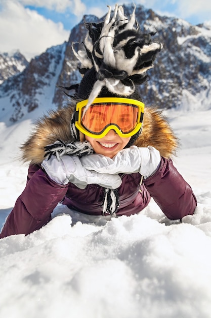 vrouw liggend op besneeuwde berg in zonnige dag met blauwe lucht en grote rots op de achtergrond